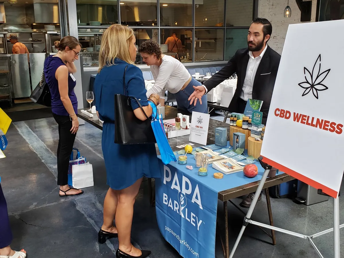 Guests stopping at a CBD wellness table during a corporate event in a restaurant space