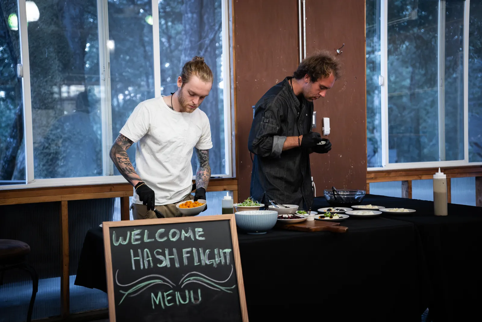 A chef preparing dinner beside a chalkboard sign reading Welcome Hash Flight Menu