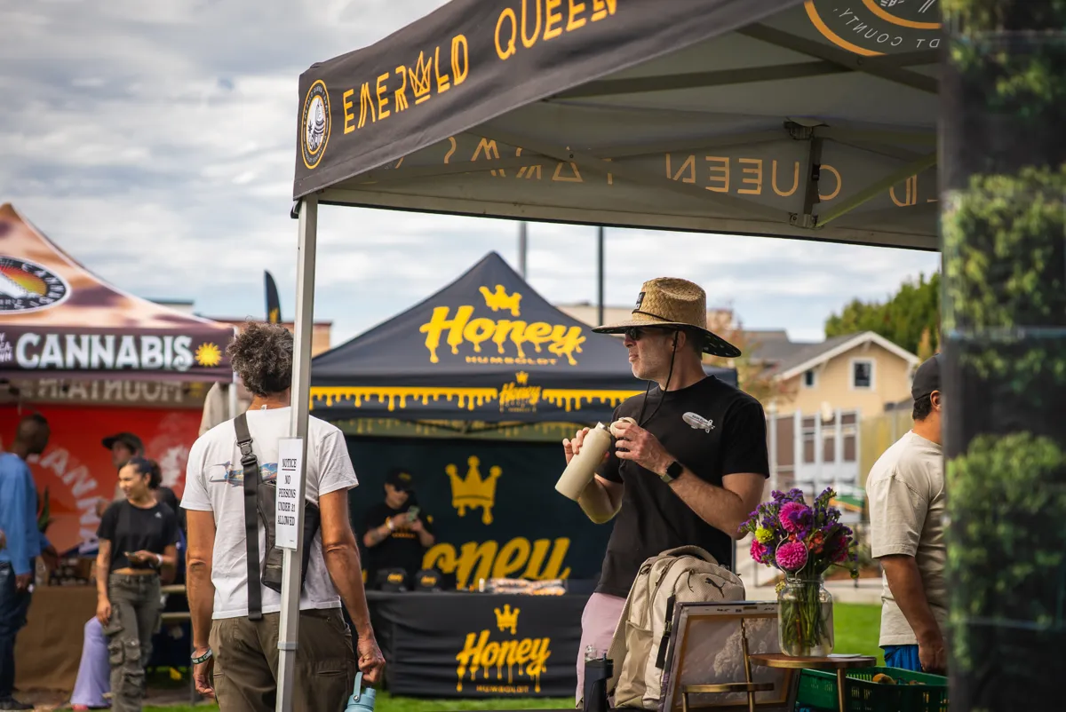 Guests walking between brand booths at an outdoor cannabis festival in Humboldt