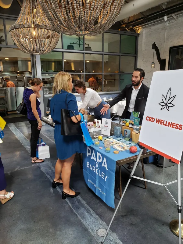 Guests stopping at a CBD wellness table during a corporate event in a restaurant space