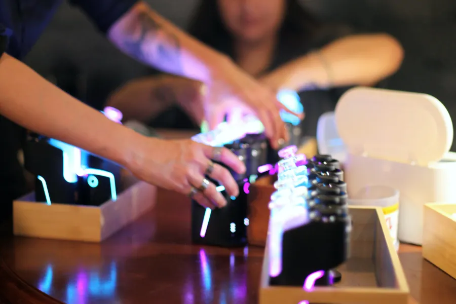 Budtender loading glowing Dr. Dabber devices into wooden trays at a dab bar