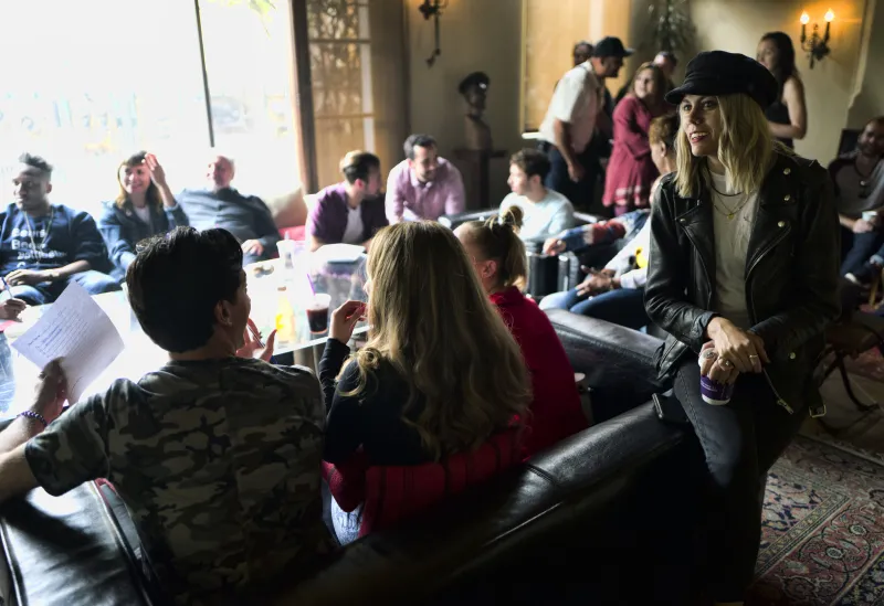 Brunch guests relaxing on leather sofas while a guest in a black cap and leather jacket smiles from the arm of the couch