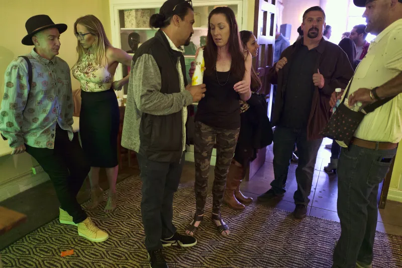 Guests chatting in small groups in a hallway at the Rita House brunch