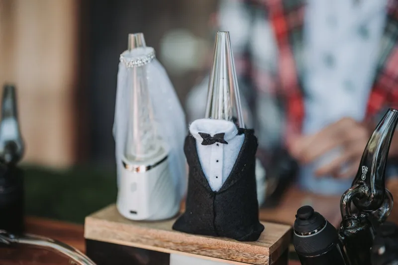 Two devices on the wedding cannabis bar dressed as a bride in a white veil and a groom in a black tuxedo
